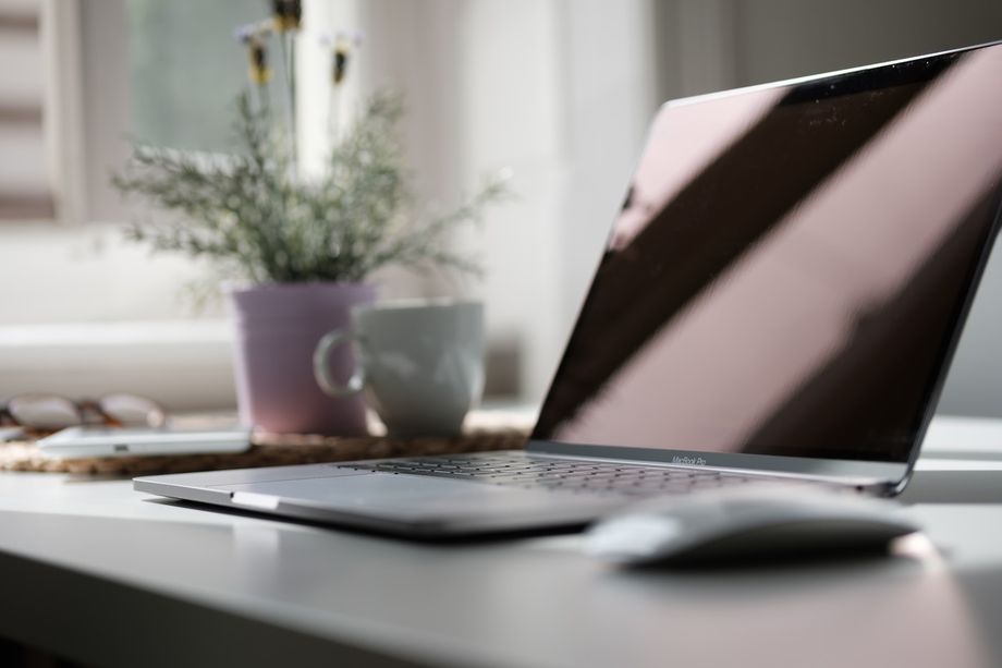 Open laptop on a bright desk beside a mug and a potted plant, ready for an online video consultation